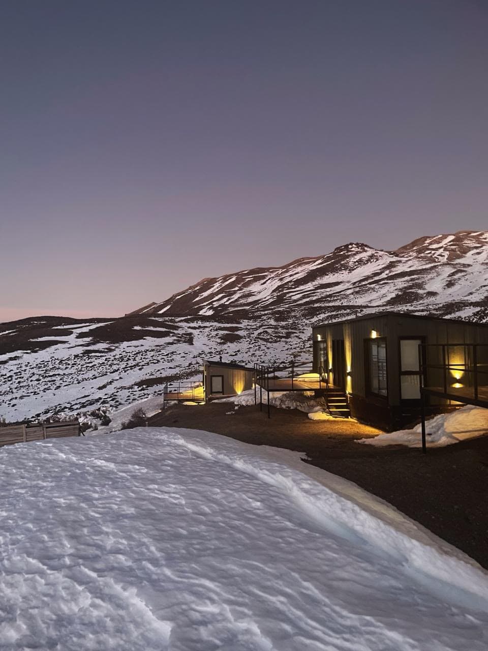Hora azul: las cabañas iluminadas con la cordillera de fondo