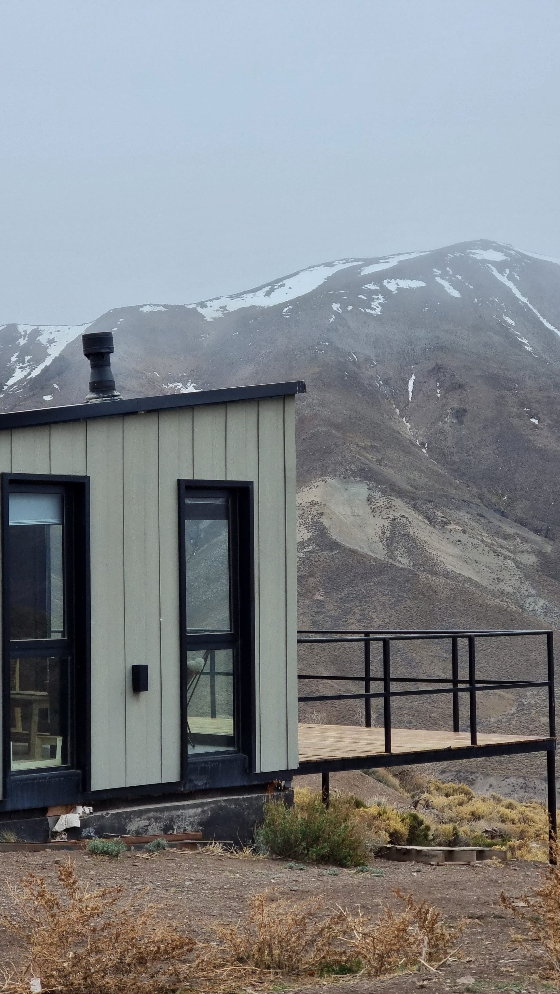 Detalle de la esquina de la Cabaña 2 con niebla y cordillera de fondo