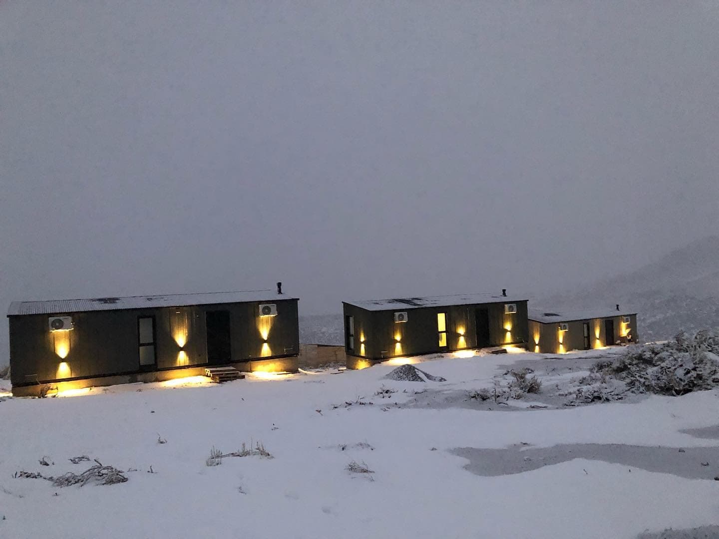 Las cabañas iluminadas al anochecer mientras nieva